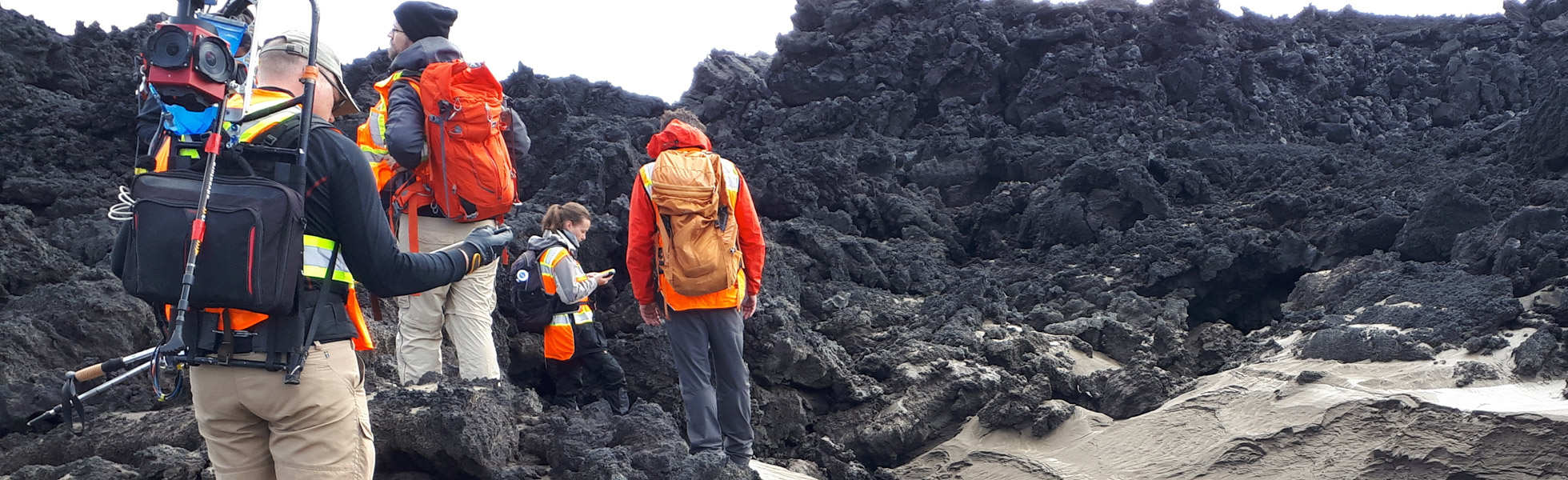 A team of researchers exploring black geological formations in Iceland.