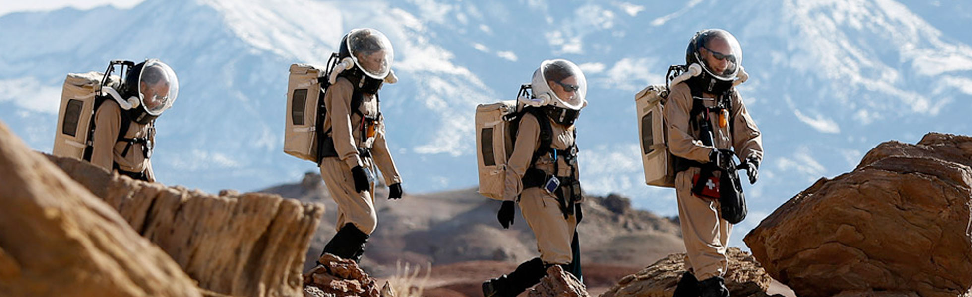 Western researchers wearing space suits crossing the desert